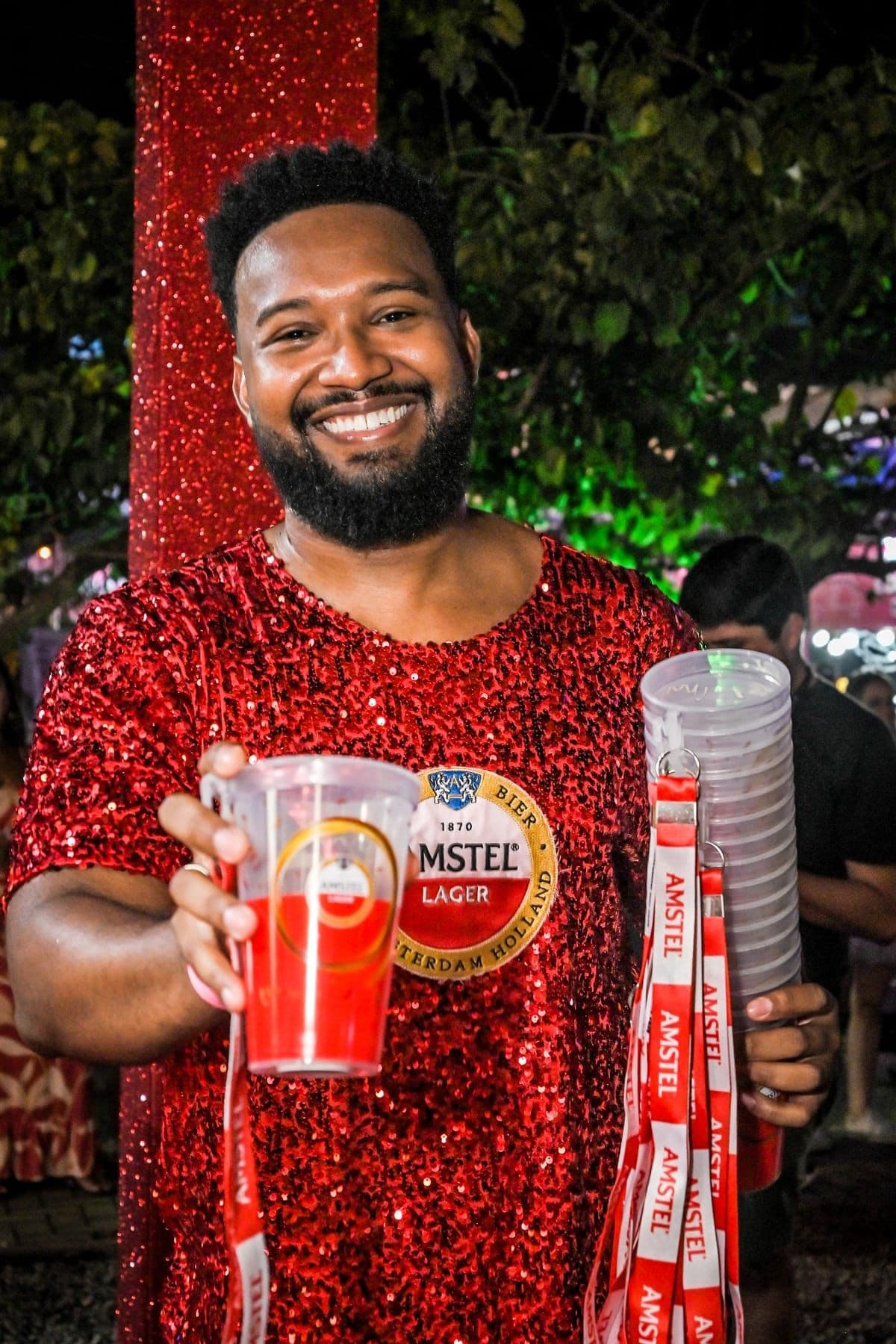 Anfitrião Amstel entregando copo e cordões da marca no evento