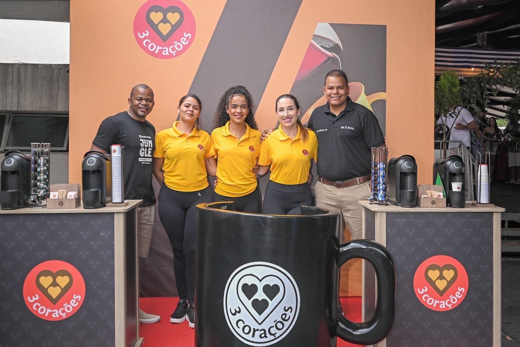 Equipe 3 Corações no bar de café com xícara gigante cenográfica